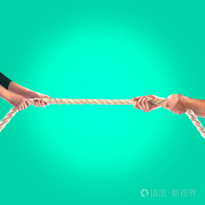 在绿色背景上用力拉绳子的人的手里.竞争理念