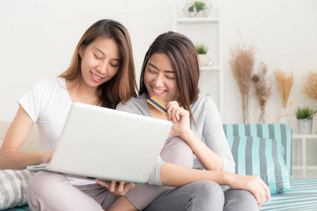 在沙发上使用笔记本电脑的年轻亚洲妇女在线购买