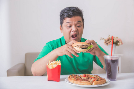过度肥胖的男子吃垃圾食品照片