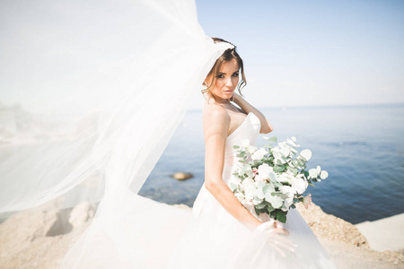 与新娘花束摆上背景大海美丽年轻的新娘