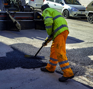 沥青路面修补或建筑工程中的工人调配新鲜沥青