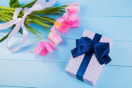 束嫩粉色郁金香与礼品盒上蓝色的木制黑色