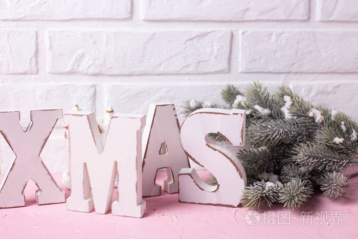木字圣诞和树枝毛皮树在粉红色的背景反对白色砖墙。选择性聚焦