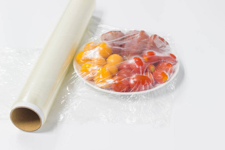 在白色背景的桌子上包上保鲜膜的水果照片