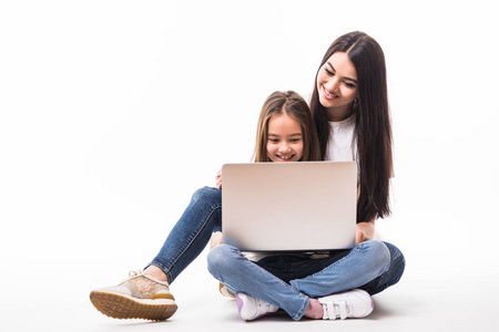 母亲和女儿与笔记本电脑玩游戏躺在地板上, 孤立的白色背景