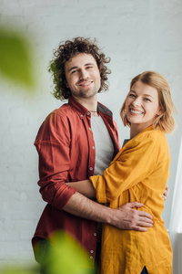 选择焦点的快乐的年轻夫妇拥抱和微笑在相机在家里