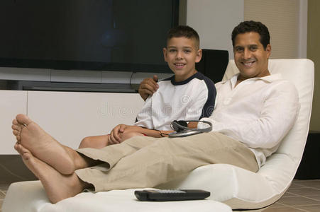 父亲和儿子坐在客厅的椅子上合影