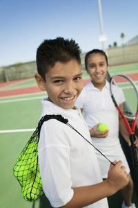 网球场上带网球器材的小男孩小女孩关注男孩肖像