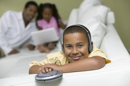 坐在沙发上听便携式cd播放器画像的男孩