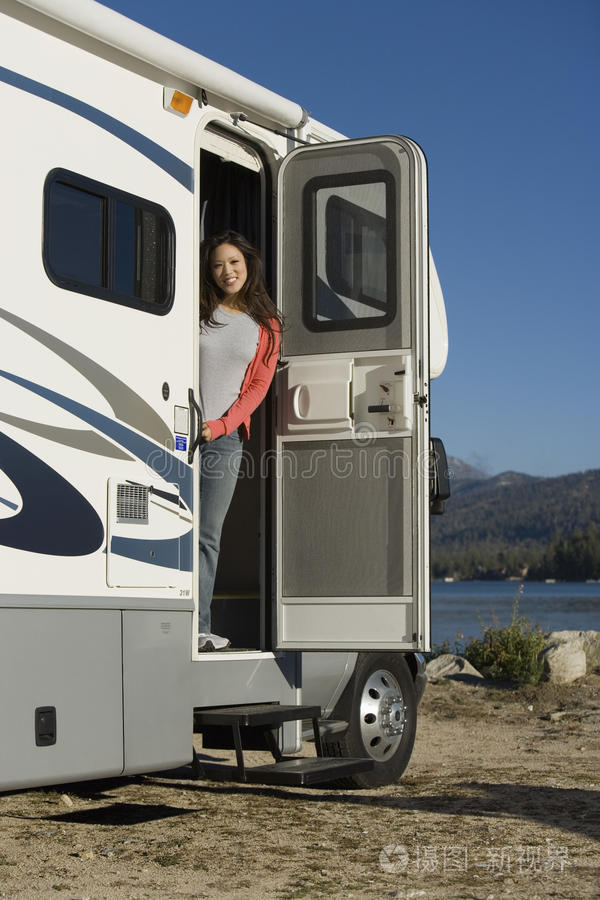 站在湖边房车门口的女人
