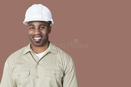 棕色背景下戴安全帽的快乐年轻建筑工人画像