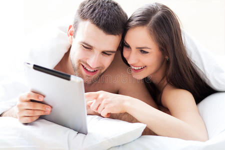 夫妻俩在床上用数字平板电脑