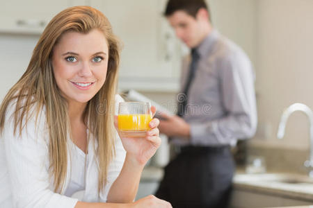 厨房里喝橙汁的年轻女子