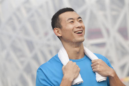 户外穿着蓝色t恤脖子上围着毛巾的微笑着的年轻运动员的肖像