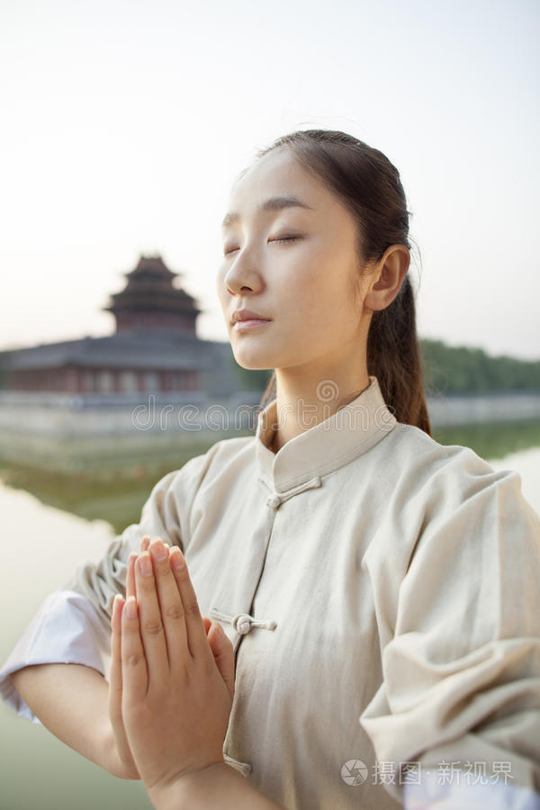 练习太极拳的年轻女子双手合十闭上眼睛在户外