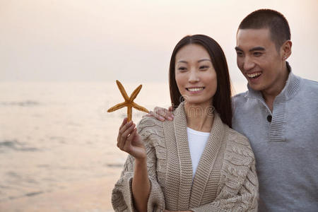 一对年轻夫妇微笑着看着贝壳