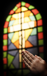 祈祷之手和彩色玻璃教堂窗户
