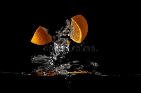 橘子片在黑色背景上溅成液体