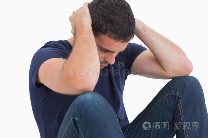 双手抱头坐在地板上的不高兴的人