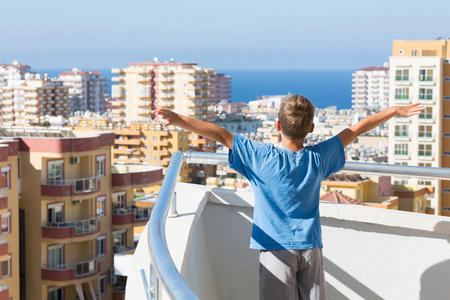 一个男孩站在旅馆的阳台上图片