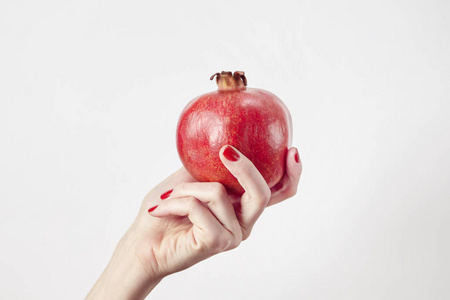 在女人的手上白色孤立的红色新鲜石榴.蔬菜和水果夏季概念照片