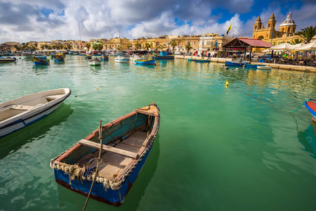 马尔萨什洛克，马耳他传统多彩马耳他 Luzzu fisherboats 在马尔萨什洛克与绿色的海洋水，蓝色的天空和棕榈树的一个