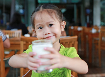 小亚洲女孩早上在餐厅喝牛奶