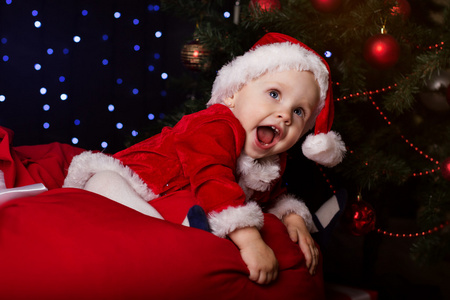 婴儿正坐在靠近圣诞树装饰