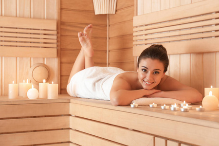 年轻女人躺在长凳在桑拿照片