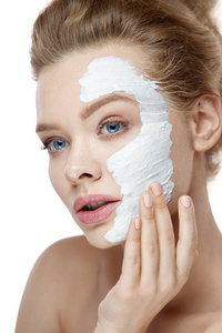 皮肤护理。年轻女子脸上应用白色面具。化妆品
