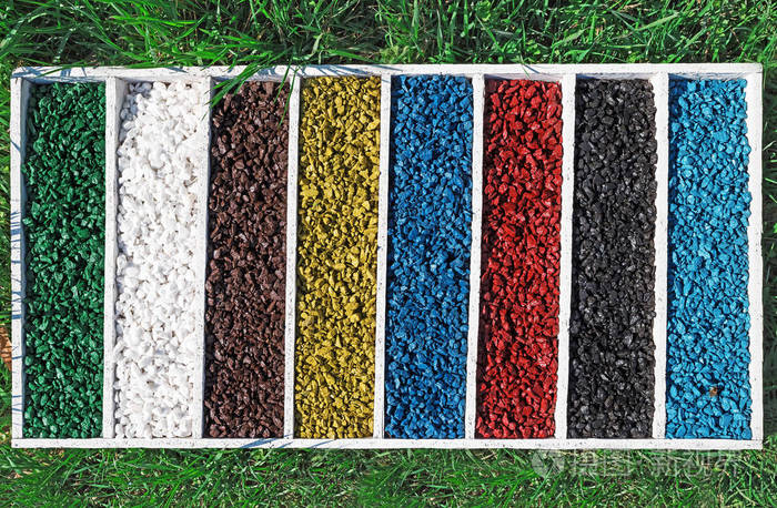 在绿色的草地上的木盒子里的彩色岩石艺术水族馆鱼罐砾石石头颜色