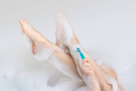 女人剃须腿用剃刀在浴室