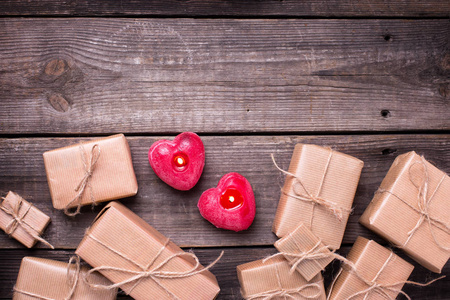 节日礼品盒与礼物和两个燃烧蜡烛的形式, 在老式的木质背景的心脏。选择性对焦。顶部视图。文本位置