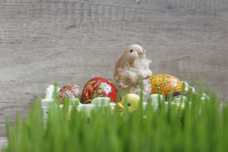 玩具复活节兔子与鸡蛋坐在篮上绿草