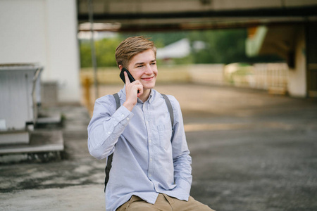 一个年轻迷人的白种男性的肖像站在户外穿着巧妙地与手机在城市