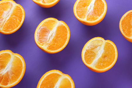在紫色的背景下, 在格子图案的水果橙切片, 对称地奠定了柑橘的流行