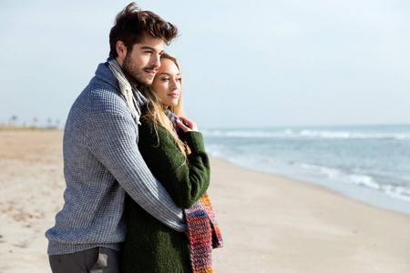 美丽的年轻夫妇在一个寒冷的爱在海滩上