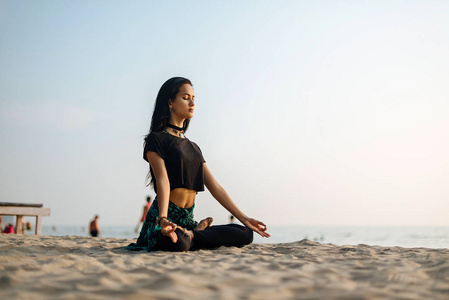 ung frisk kvinna utvar yoga p stranden vid solnedgngen