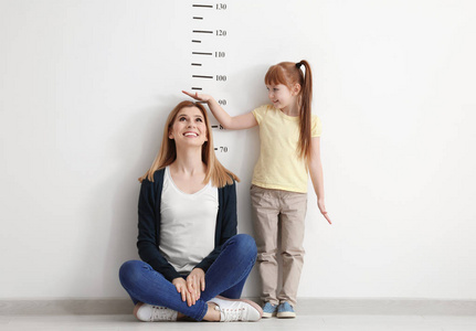 测量母亲身高的小女孩照片