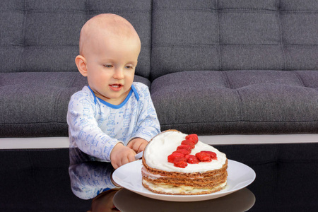 一个小男孩的第一个生日庆祝。小男孩用勺子吃生日蛋糕, 生日快乐。孩子在桌与蛋糕