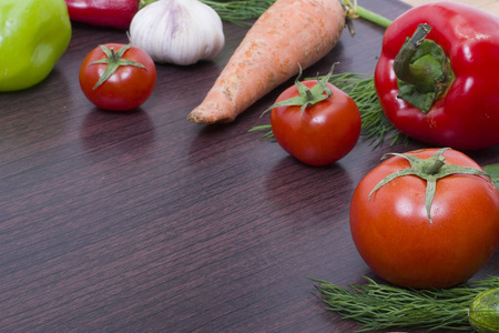 蔬菜的概念在一个木制的背景。桌上放着绿色和红色胡椒的胡萝卜。棕木背景的新鲜蔬菜