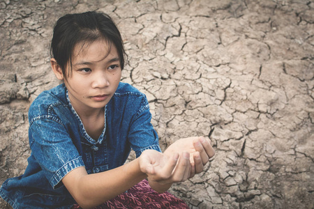 哀伤的女孩祈祷雨在破裂的干燥地面, 概念干旱和缺水危机