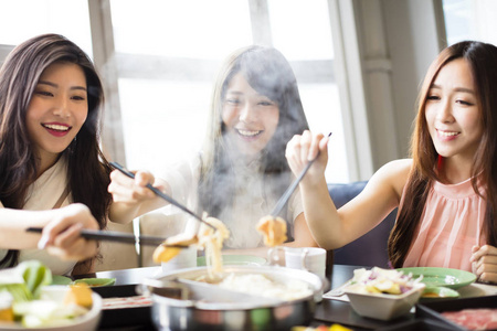 组年轻快乐的年轻妇女组吃火锅照片