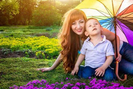 年轻的母亲和她的小儿子在花园里玩。母亲节的概念