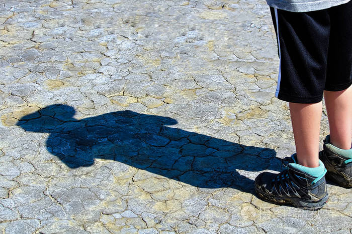 woung男孩在干泥上的影子