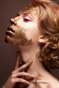 年轻女孩与创意化妆和她脸上的纹理。覆盆子箭头与金黄色素的美丽模型
