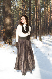 在冬季的森林里的长裙子的女孩