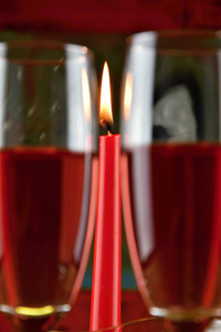两杯玫瑰酒和一支燃烧的蜡烛图片
