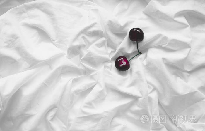 一颗樱桃床单皱巴巴的白色背景上的顶视图