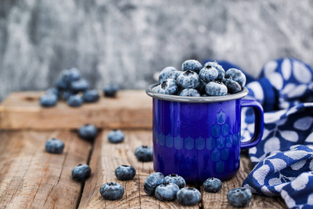新鲜成熟的蓝莓和蓝色搪瓷杯